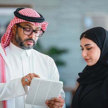 Two Middle Eastern professionals discussing something on a tablet.