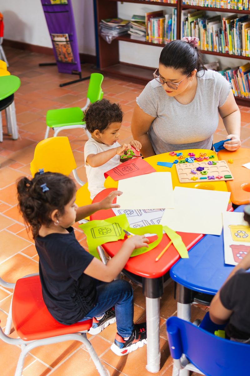Preschoolers cutting and pasting recycling bin cutouts during arts and crafts class