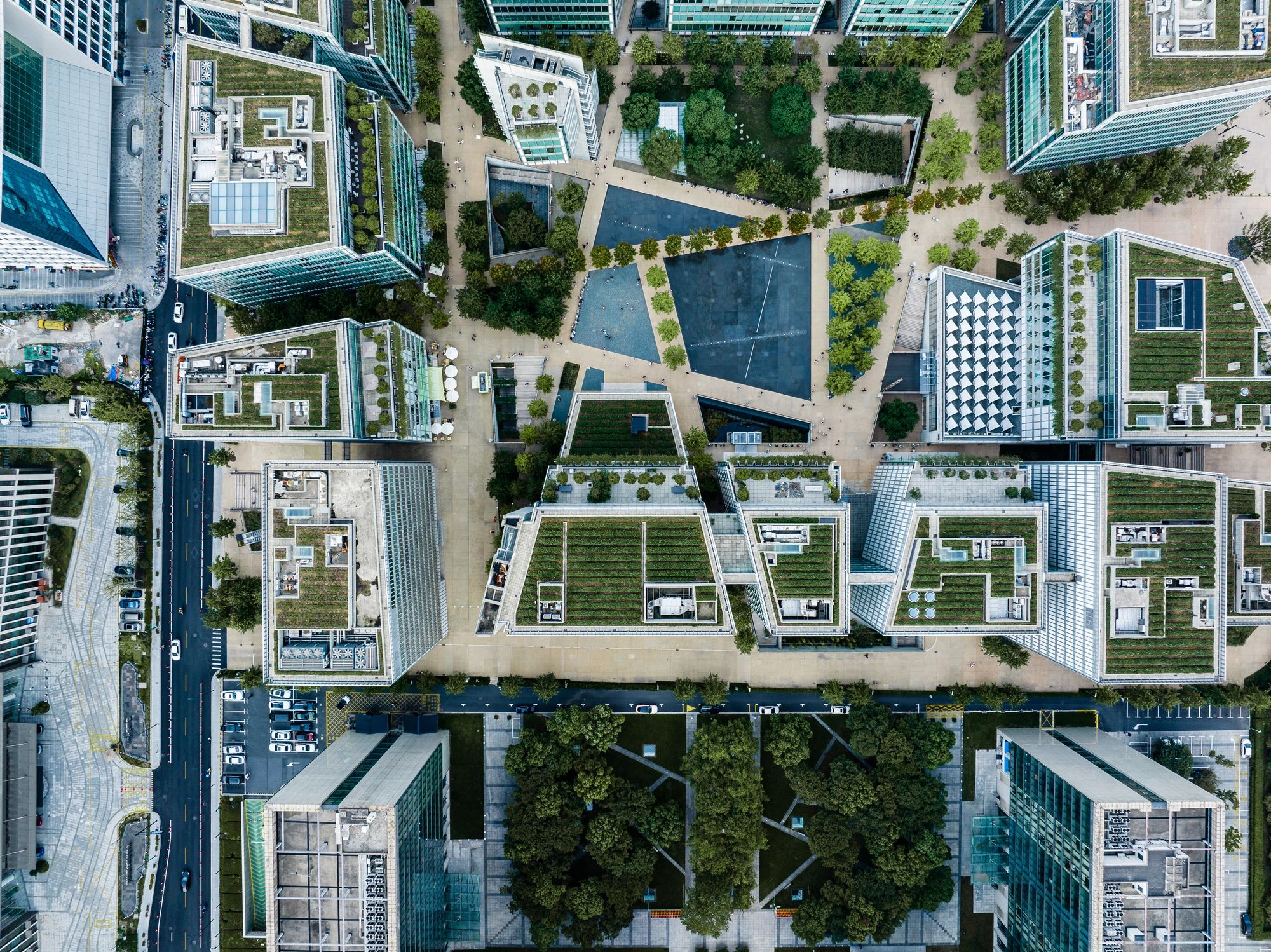 Aerial view of a modern urban park surrounded by buildings with rooftop gardens.