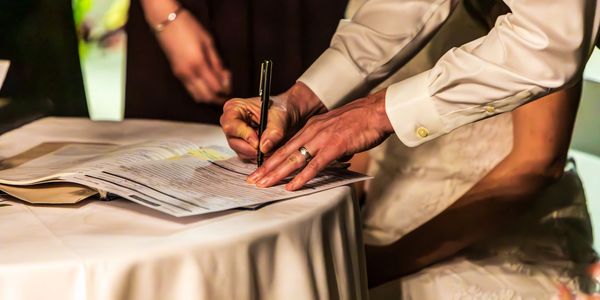 A person in formal attire signing a document on a table.
