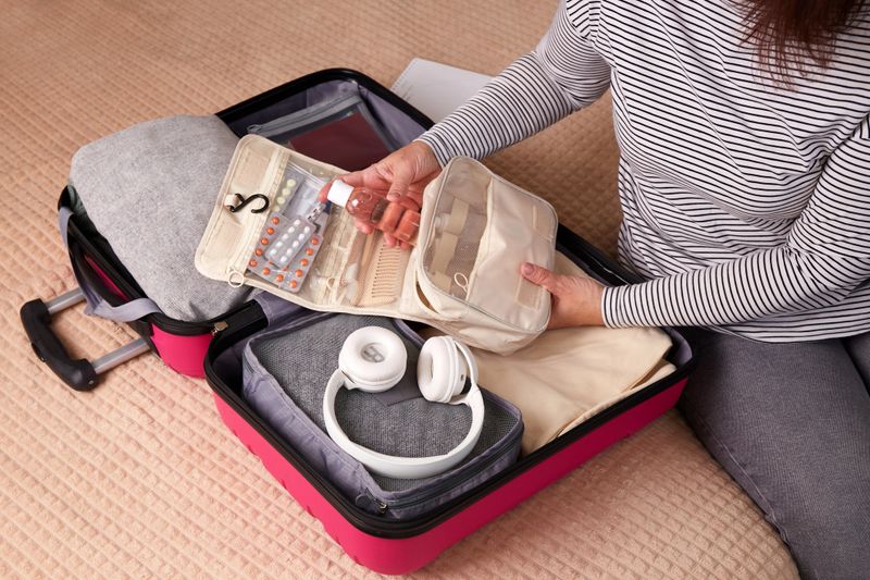 A woman puts hygiene products, clothes, and travel accessories in a suitcase. Getting ready for the trip.