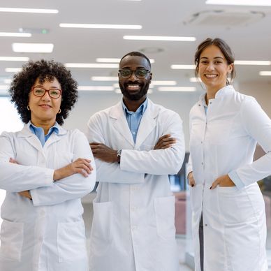 Three medical professionals smiling confidently in lab coats.