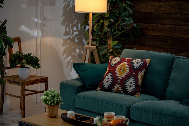 This stylish living room features a green sofa with pillows and plants, creating a vibrant atmosphere