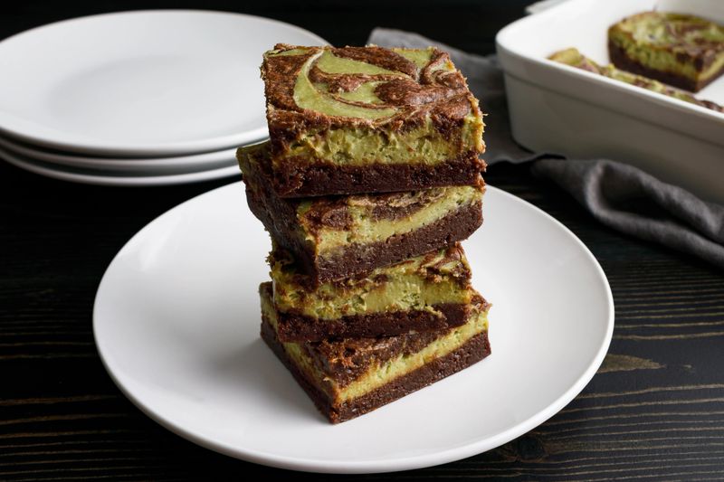 Dark chocolate brownies with green tea cream cheese filling stacked on white dessert plate