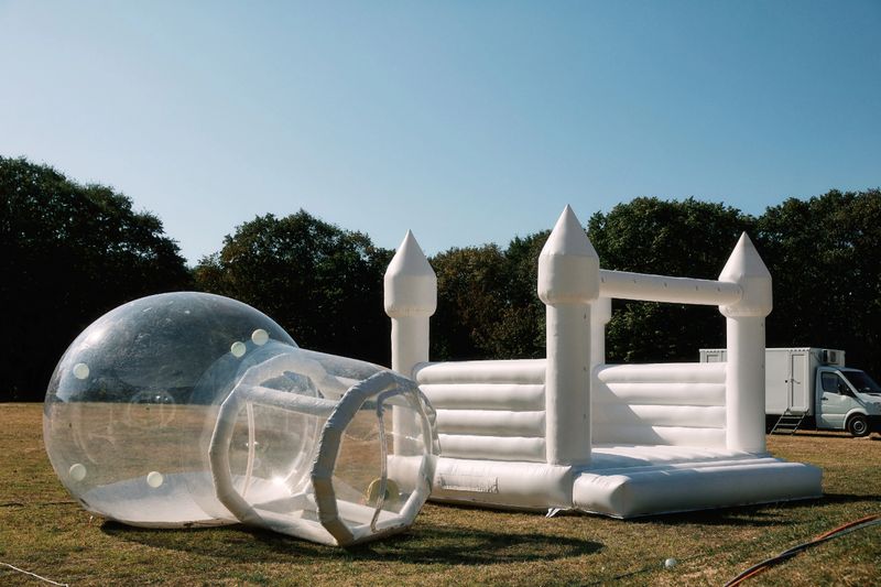 A bouncy castle and balloon prepared for children to play outdoor. Forest in the background.