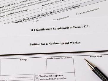 Close-up of U.S. immigration forms for nonimmigrant worker petitions with a pen.