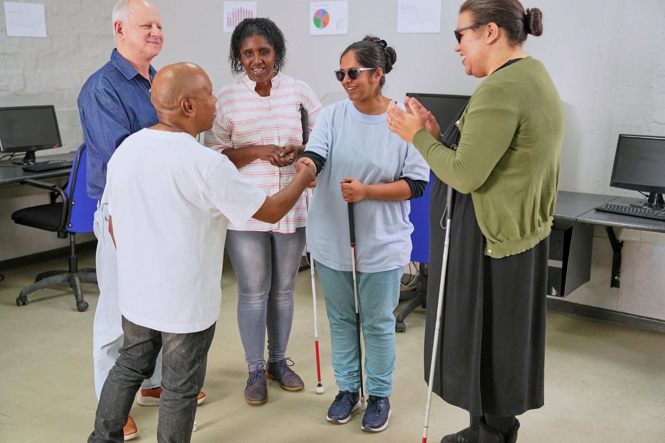 "Group of five visually impaired people standing together in a circle, connecting and supporting one