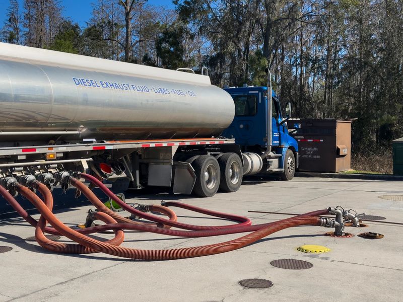 A fuel tanker truck making a delivery in Live Oak, Florida. The complex network of hoses and valves ensures the efficient transfer of diesel exhaust fluid, lubricants, fuel, and oil, keeping transportation and industry moving smoothly.