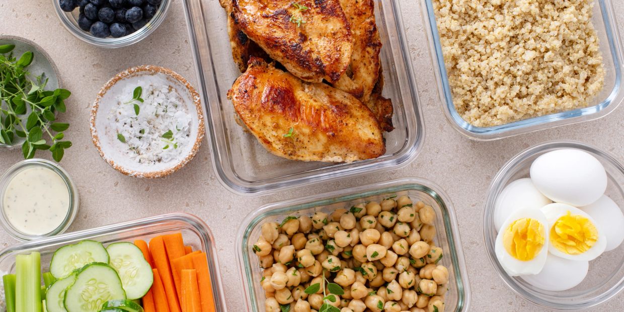 Healthy meal prep with grilled chicken, quinoa, chickpeas, boiled eggs, and fresh vegetables.