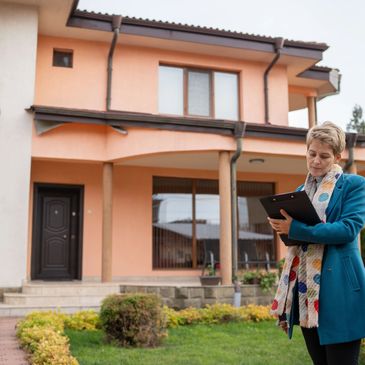 Appraiser with clipboard outside house.