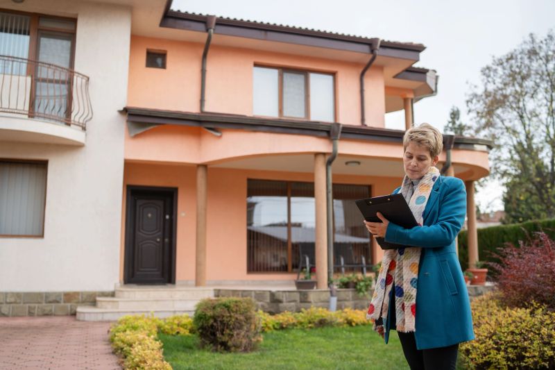 A delighted woman holds a folder outside her stylish residence, showcasing confidence and warmth, reflecting the beauty of modern architecture and a fulfilling personal life.