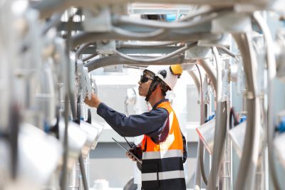 Worker inspecting pipes wearing safety gear.