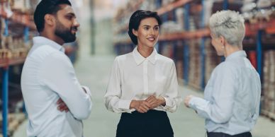 Three professionals discussing work in a warehouse.