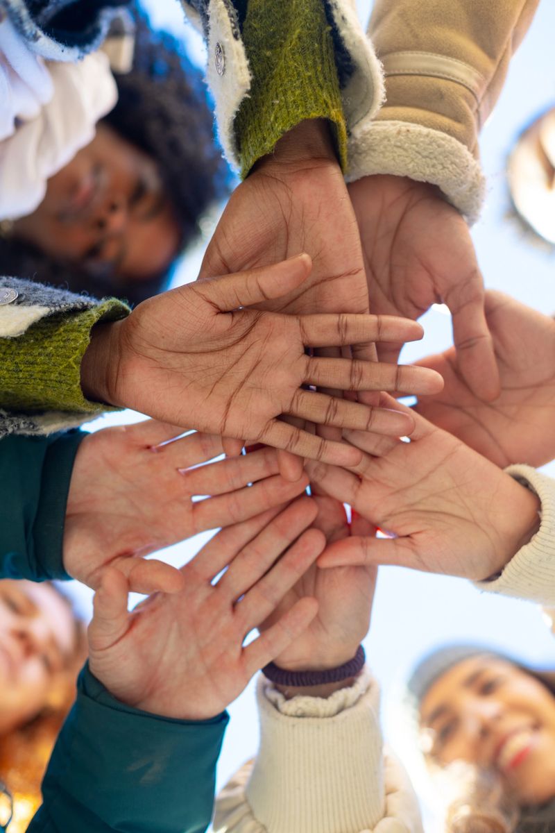 Group of diverse students joining hands in a circle, symbolizing teamwork, collaboration, and unity