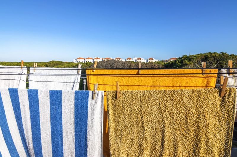 Close-up of towels hanging with wooden clothespins , with the blue sky in the background. Concept of cleanliness and freshness.