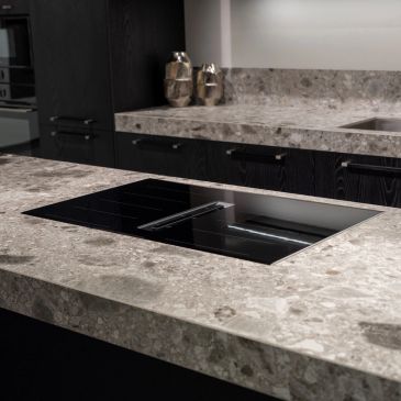 Modern kitchen with sleek black stovetop and marble countertops.