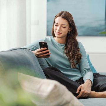 Woman seated during a wellness session, glancing at her phone with a calm, attentive expression