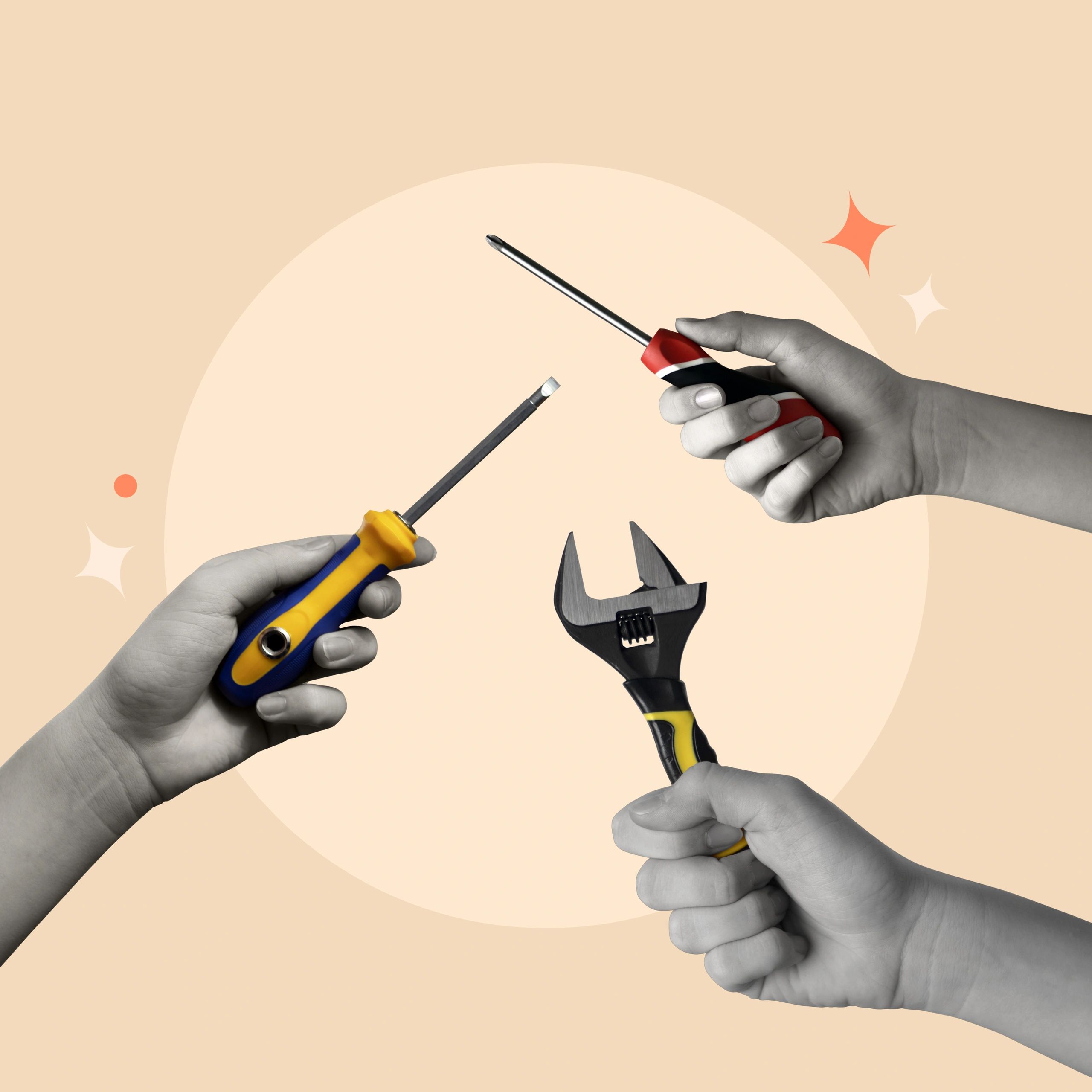 Hands holding different types of screwdrivers and a wrench on a beige background.