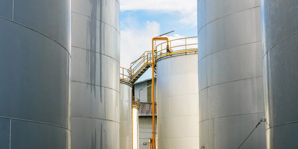 Large industrial storage tanks with metal staircases and railings under a blue sky.