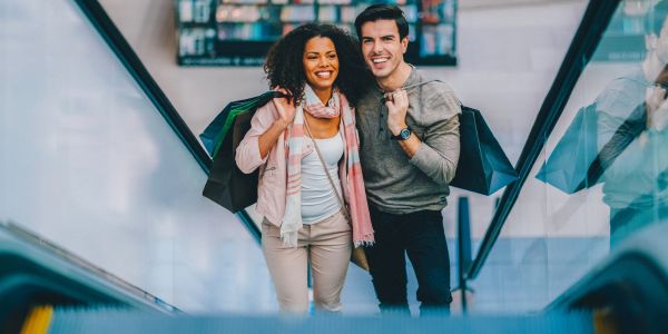 Happy couple carrying shopping bags on an escalator.