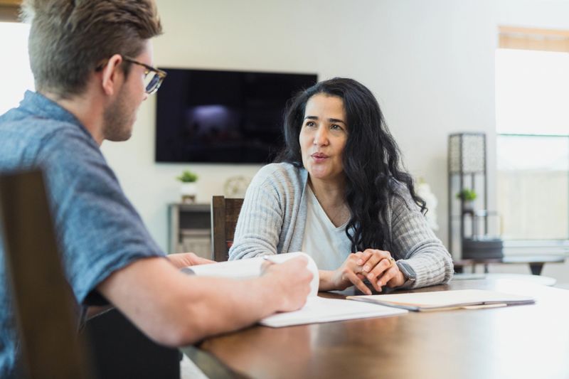 Mid adult Hispanic woman and young man in a counseling session, discussing paperwork.