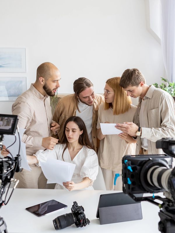 Film crew discusses script on set with cameras and equipment around.