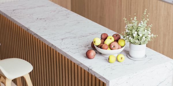 Modern kitchen island with marble countertop and wooden stools.
