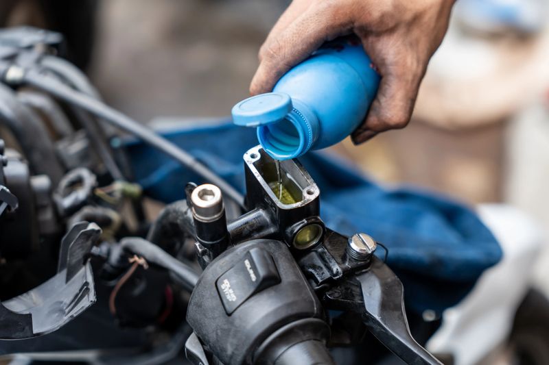 Mechanic check and Add Brake Fluid on motorcycle brake reservoir in garage, motorcycle repair concept