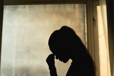 Silhouette of a person in deep thought by a window.
