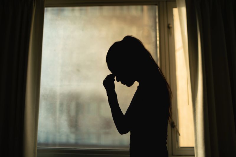 Unhappy woman at home in city apartment.