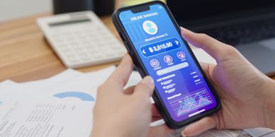 Person holding smartphone displaying an online banking app with financial details.