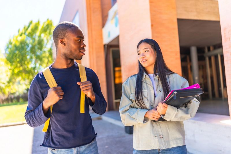 Two female and male multiracial friends talking at the entrance of the university