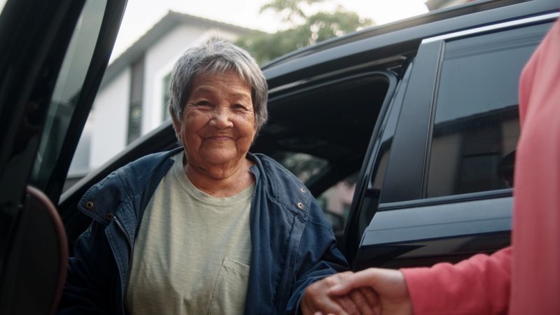 Young woman helping a senior woman out of the car.