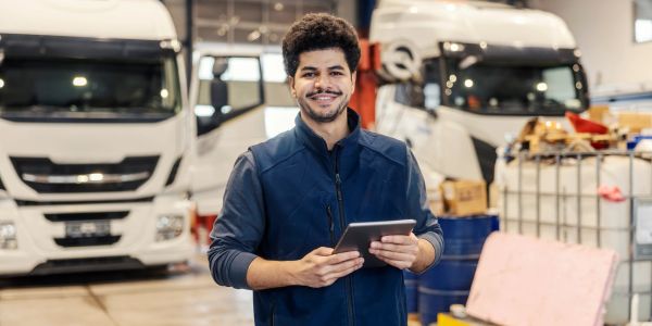 Man holding tablet in front of trucks.
