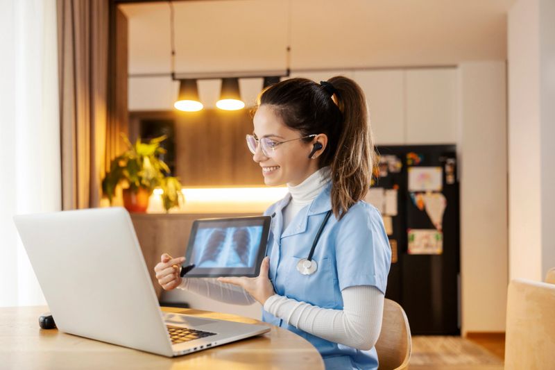 Friendly doctor pointing on x-ray scan on tablet at online consultations form home.