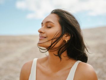 Woman enjoying a breeze with eyes closed.