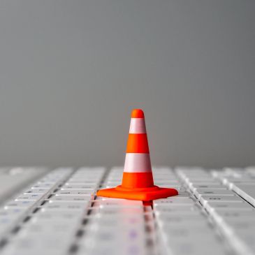 Mini traffic cone placed on a white computer keyboard.