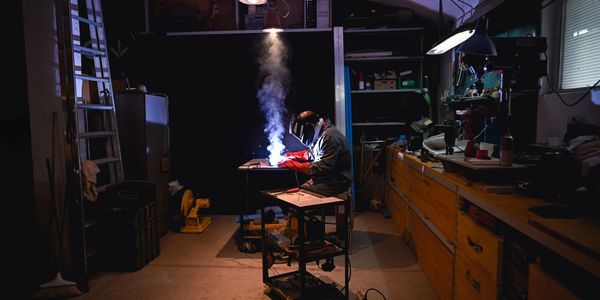 A welder working intensely in a dimly lit workshop.