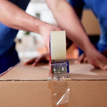 Person sealing a cardboard box with tape.