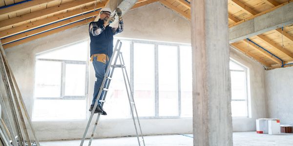 Electrician working on wiring inside a house under construction.
