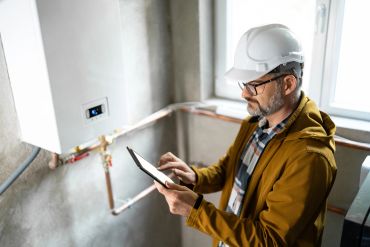 Engineer inspecting boiler system with tablet.