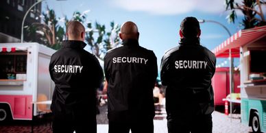 Three security personnel stand with backs facing the camera outdoors.
