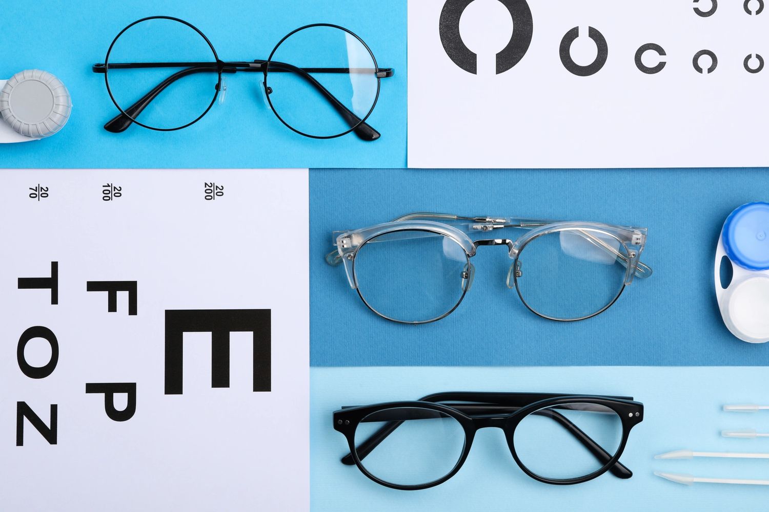 Three pairs of eyeglasses with eye test charts and contact lens cases on blue background.