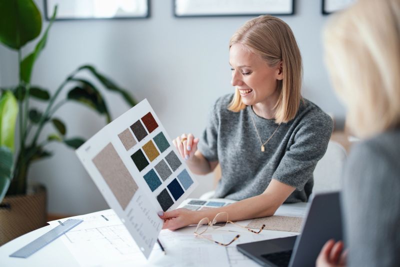 A woman in a modern design studio holds fabric samples, engaging in creative discussion.