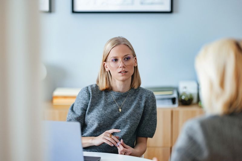 A professional conversation between two colleagues in an office environment, discussing potential ideas and strategies. The workspace is modern and light, fostering a reflective and collaborative mood.