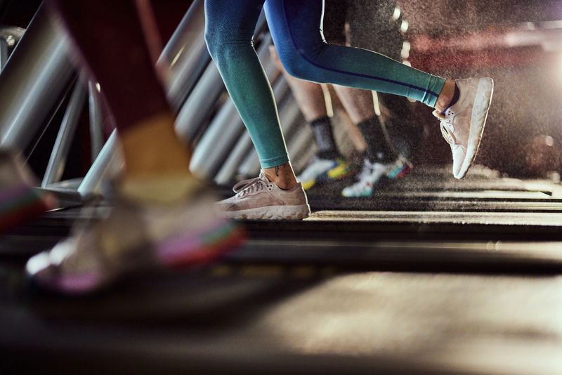 Unrecognizable athletic woman exercising on treadmill in a health club. Copy space.