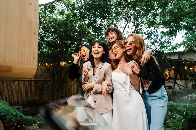 Group of Friends and Newlywed Enjoying a Fun Photo Booth Session with Playful Props and Laughter