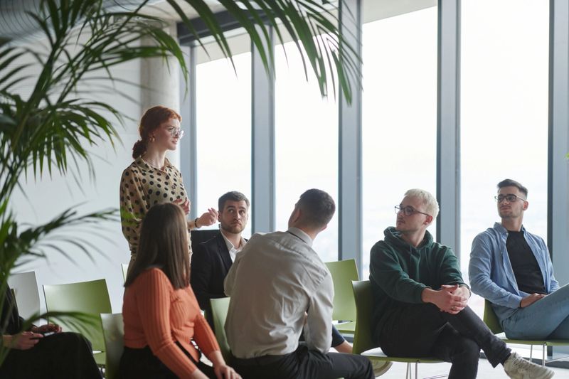 A diverse group of business professionals sits attentively in a modern office, actively participating in a training session led by an instructor, focusing on the latest technological advancements in the business world