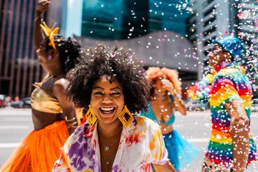 Joyful people celebrate with confetti in a colorful street party.