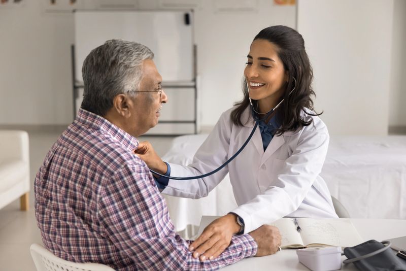 Latin cardiologist check heart rate of older male patient with stethoscope, monitoring heart rate conditions, to protect or manage age-related cardiovascular issues, coronary artery disease prevention